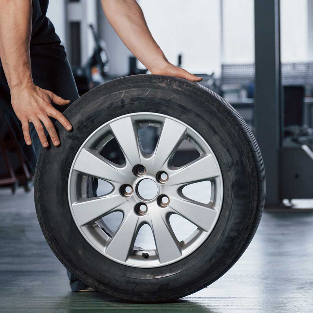 Mekaniker med hjul og aluminiumsfelg i verksted